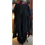 Two black graduation gowns one with a hood with red trim and the other with black applique trim to