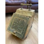 A Victorian brass coal scuttle with floral design cover, raised on panelled feet with liner and