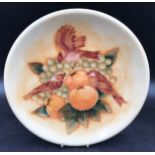 A Moorcroft wall charger decorated with birds and fruit 26.5cms d and impressed base marks.Condition