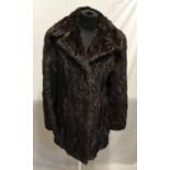 A brown mid-length mink coat with 2 x hook and eye fastenings and black silk lining. Measures