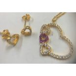 A gold heart shaped pendant necklace on chain marked 21k set with clear and pink stones together