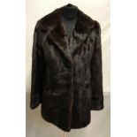 A mid-length brown mink coat with 2 hook and eye fastenings and brown silk lining. Measures 75cms