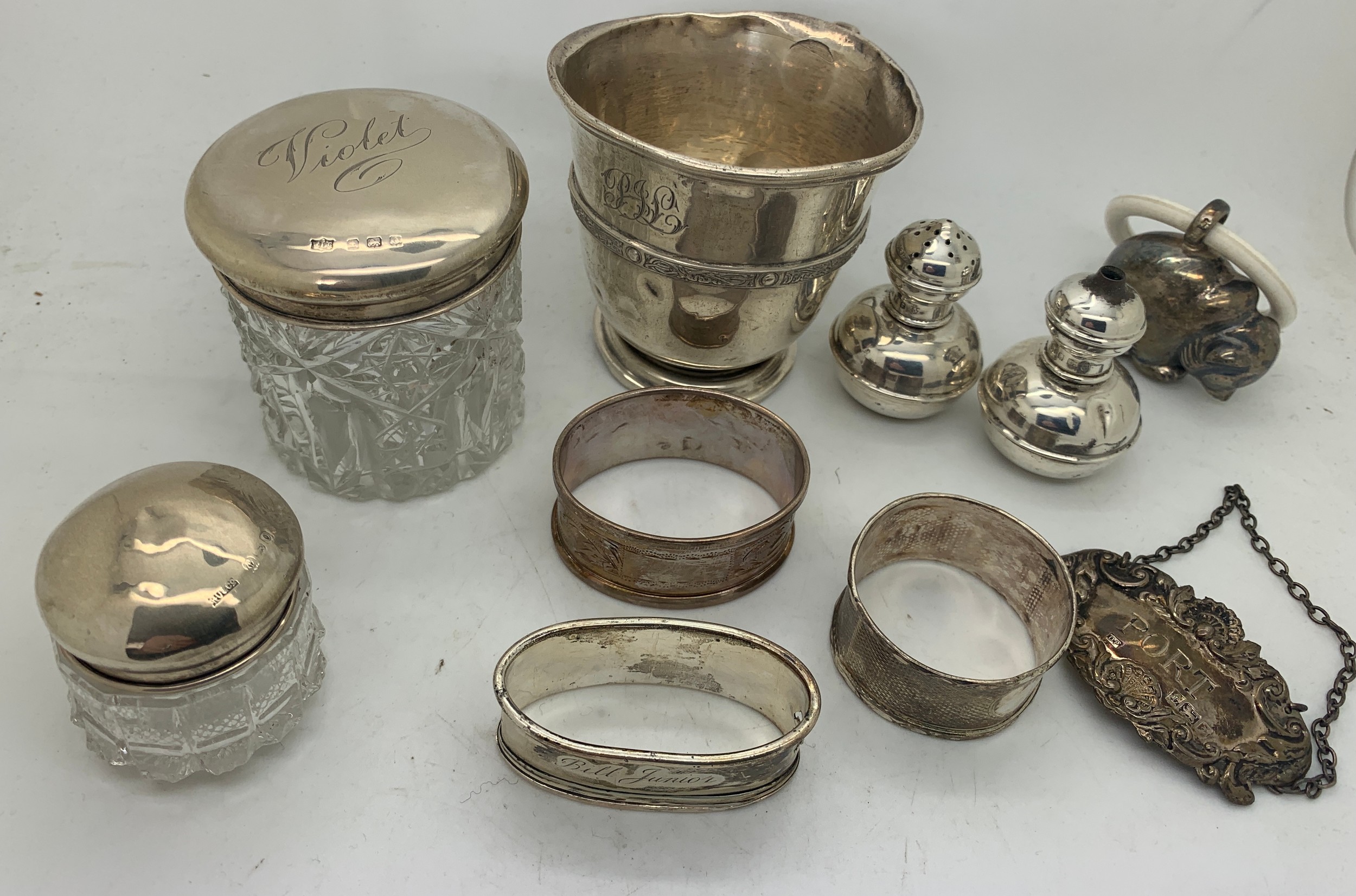 Hallmarked silver items and a child's rattle marked .800 to include napkin rings, Port label, mug