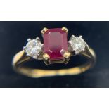 A three stone ruby and diamond ring the central ruby flanked by diamonds set in 18ct gold. Size Q.