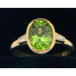 Peridot and diamond ring set in 18ct gold, central peridot flanked by baguette cut diamond. Size M/