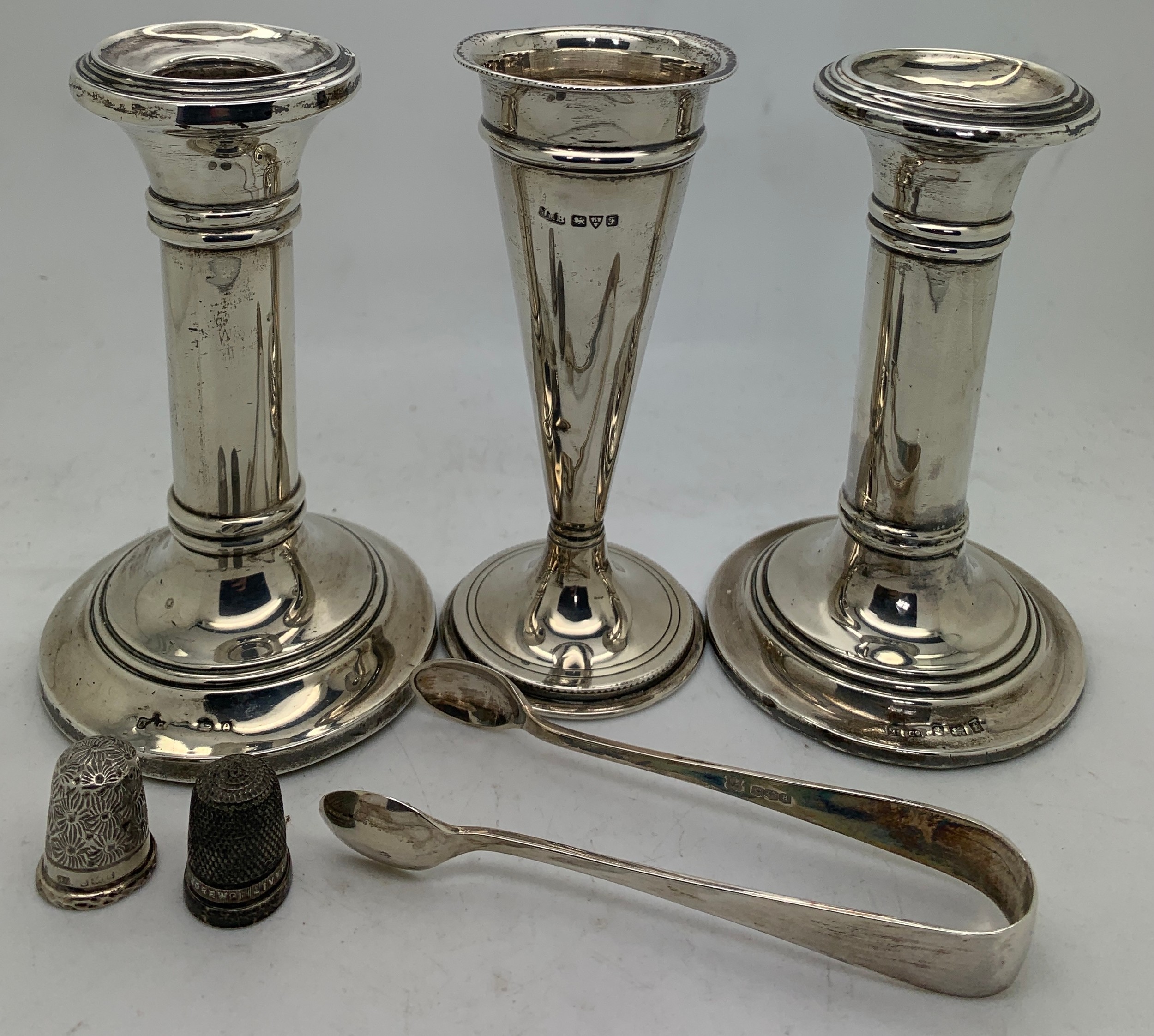 Hallmarked silver to include a pair of candlesticks with weighted bases, vase, sugar tongs, 2