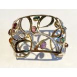 A 14CT YELLOW GOLD OPEN WORK CONTEMPORARY DESIGN BANGLE, mounted with 15 cabochon amethyst,