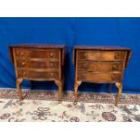 A PAIR OF DROP LEAF SERPENTINE SHAPED MAHOGANY SIDE CABINETS / TABLES, with feathered mahogany
