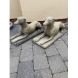 A PAIR OF STONE GARDEN ORNAMENTS, in the form of two dogs lying down, 70cm long approx.