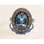 AN 18CT WHITE GOLD AQUAMARINE, BLACK DIAMOND & DIAMOND RING, with central oval cut aquamarine in a