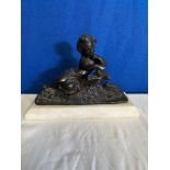 A SMALL BRONZE ORNAMENT OF A GIRL READING, on a white marble base