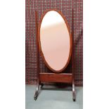 A CHEVAL MIRROR, with cross banded frame to oval mirror, raised on mahogany frame with lion paw