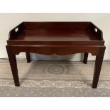 A MAHOGANY BUTLERS TRAY TABLE, with lift up tray top, having pierced handles to the left and