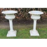 A GOOD QUALITY PAIR OF HEAVY CAST IRON GARDEN URNS, raised on fluted pillars on platform base, 82.