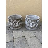 A PAIR OF ROUND STONE PLANTERS, with cherub decoration, 27cm wide x 24cm tall approx.