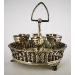 A VICTORIAN SILVER PLATED EGG CUP HOLDER WITH CUPS, the holder in the form of a basket with weaved