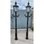 A PAIR OF CAST IRON GARDEN / DRIVEWAY LAMPS, with glazed lantern tops, and scrolling foliage motif t