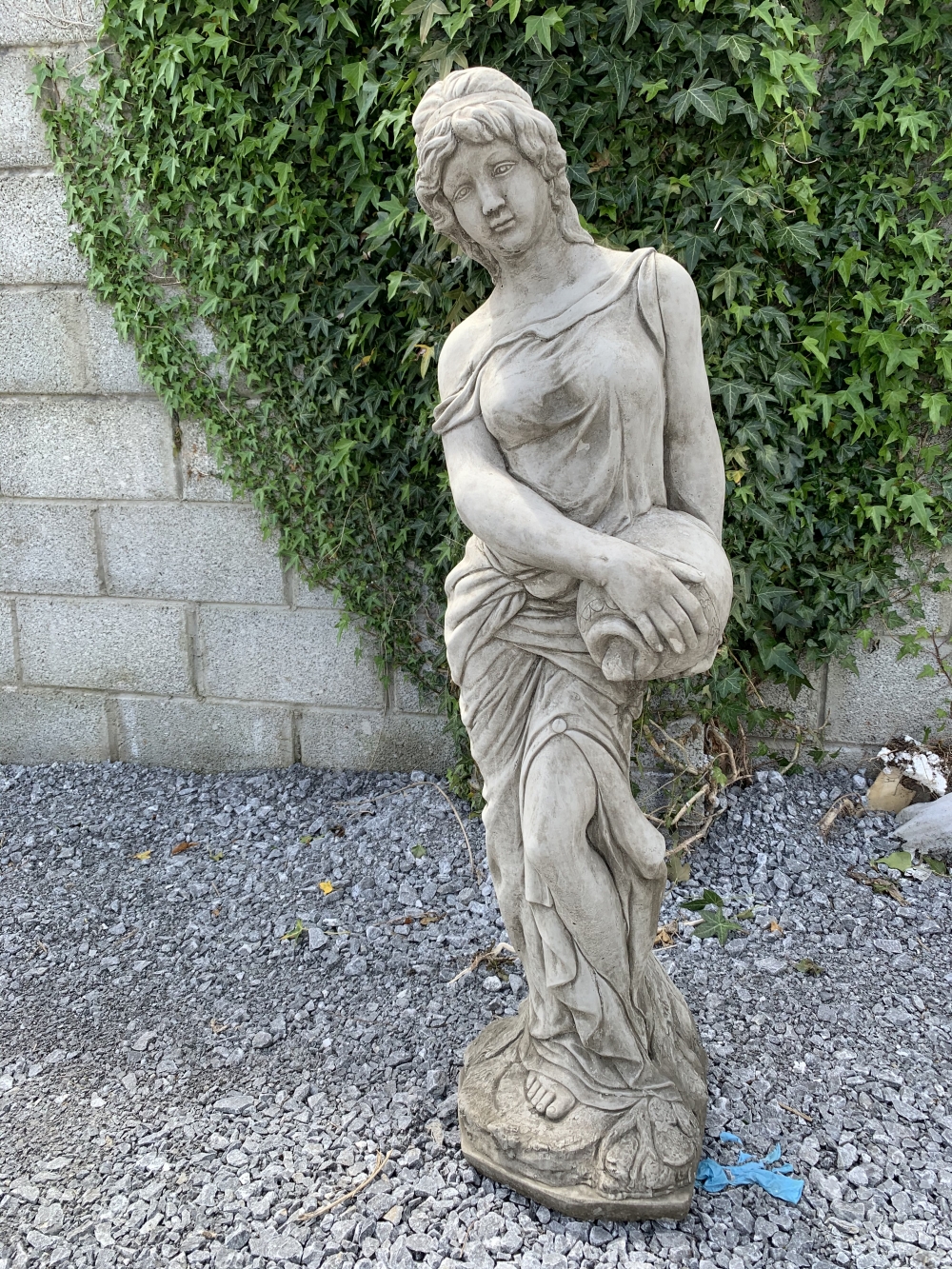 A STONE GARDEN ORNAMENT IN THE FORM OF A FEMALE FIGURE, holding an urn, size: 4ft tall approx.
