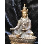 A TIBETAN BRONZE FIGURE OF PADMASAMBHAVA, seated in the lalitasana pose, holding a skullcup in his l
