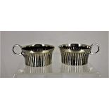 A PAIR OF SILVER PLATED SALTS, in the form of cups, with small handles and fluted bodies