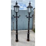 A PAIR OF CAST IRON GARDEN / DRIVEWAY LAMPS, with glazed lantern tops, and scrolling foliage motif t