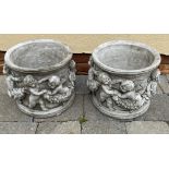 A PAIR OF CIRCULAR SHAPED GARDEN PLANTERS / POTS, decorated with cherubs to the body, 23cm tall x 26