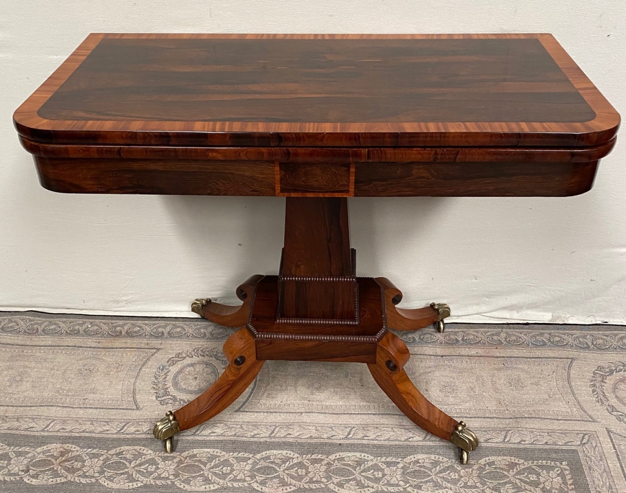 A FINE REGENCY ROSEWOOD FOLD OVER CARD TABLE, with cross-banded top having rounded corners, over a d