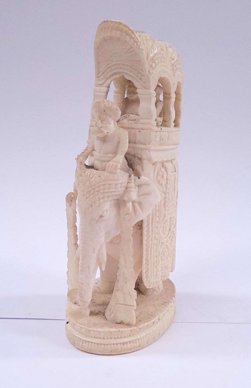 A FINELY CARVED IVORY FIGURE OF AN ELEPHANT CARRYING A HOWDAH, with a driver and two passengers with