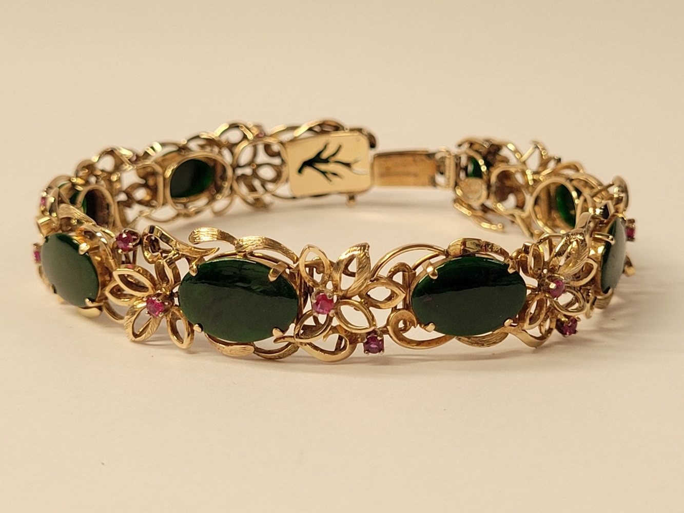 A 14CT YELLOW GOLD JADE AND RUBY BRACELET, 19cm long. Floral design setting. Marked 585 14K.