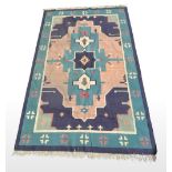 A KELLIM RUG, Design: three large multi-coloured Aztec motifs in the central field, surrounded by ge