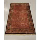 A GOOD QUALITY PERSIAN PURE WOOL RUG, with burgundy main ground, having dense floral design all over