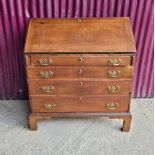 AN OAK DROP FRONT SECRETAIRE DESK, four graduated drawers each with brass swing handles, raised on b