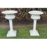 A FINE PAIR OF HEAVY CAST IRON RAISED COLUMN GARDEN URNS, white in colour, Victorian in style, with