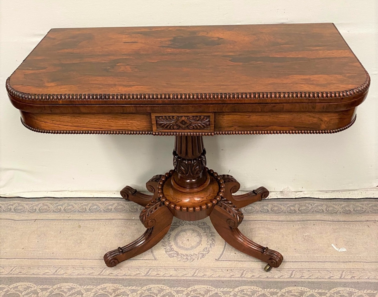 A VERY FINE REGENCY ROSEWOOD FOLD OVER CARD TABLE, with gadrooned rim to the curved fold over top, a