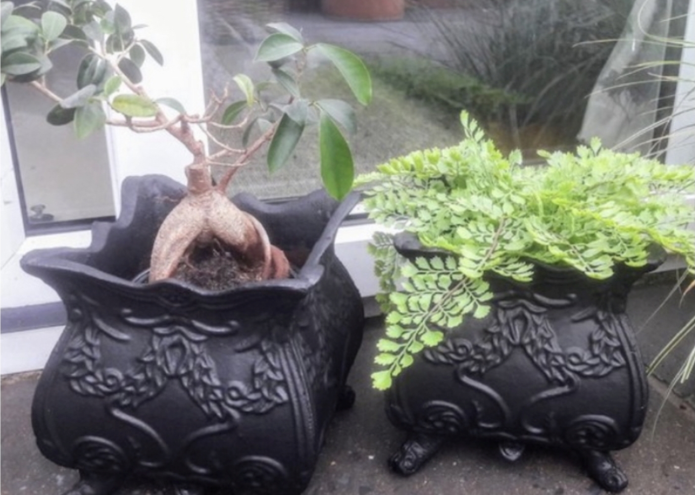 A PAIR OF BLACK COLOURED GARDEN PLANTERS, shaped body with foliage motif to the body. 12 x 12 x 12 i