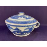 A Chinese porcelain blue and white chamber pot and cover, decorated with lakeside dwellings in a