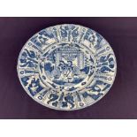 A Japanese blue and white porcelain dish, depicting seated men and women in a garden, 31cm diameter