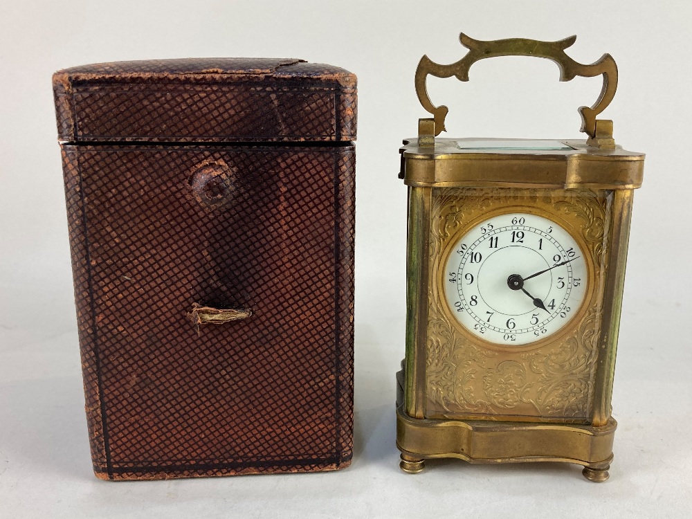 A brass carriage clock with white circular enamel dial and arabic numerals within gilt scroll