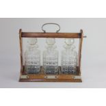 A Victorian oak three decanter tantalus with metal mounts and carry handle, lock and key, on