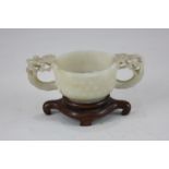A Chinese jade two handled cup, with a rounded bowl carved with studded decoration, the two