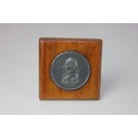 A circular metal plaque of Admiral Lord Nelson in profile, mounted in a wooden frame, 8cm square