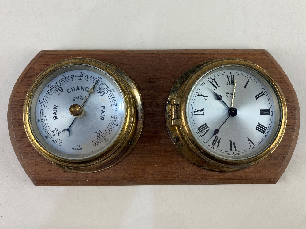 A Sestrel brass cased bulkhead barometer and alarm clock on wooden mount, 23.5cm wide