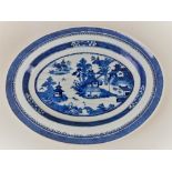 A Chinese porcelain blue and white oval platter, decorated with a scene of a riverside village,