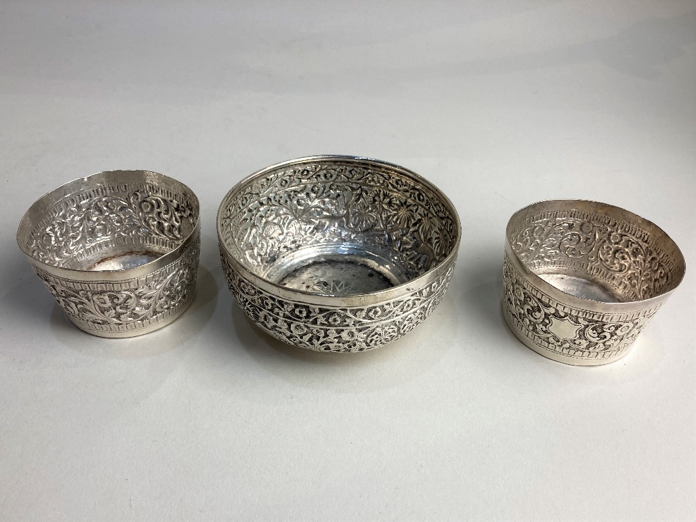 An Indian silver circular bowl embossed with animals in a forest, 9cm and a pair of small circular