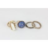A domed cluster ring set with round blue stones in yellow gold, a white stone eternity ring, a white