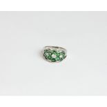 A diamond and green tsavorite ring set with three round diamonds and fourteen green garnets in