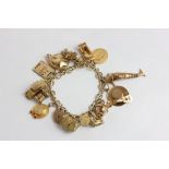 A gold charm bracelet hung with a padlock clasp and various pendants including a half sovereign 67.