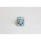 An aquamarine and diamond dress ring the step cut stone within a micro set diamond border in 18ct