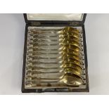 A set of twelve French 800 silver gilt tea spoons, with scroll design, in fitted case (a/f), 9.5oz