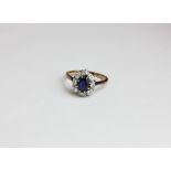 A sapphire and diamond cluster ring the oval cut stone claw set within a border of eight brilliant